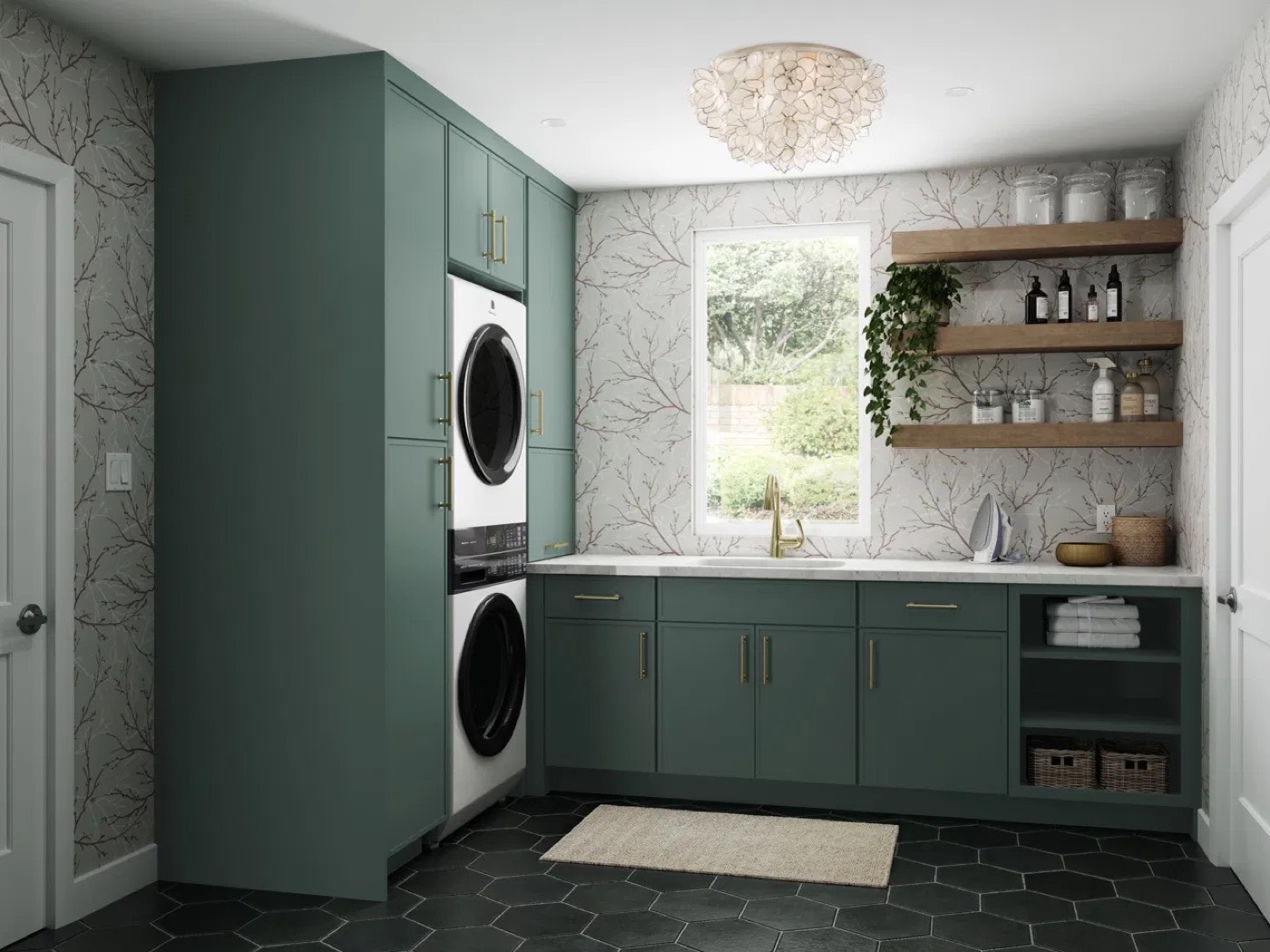 Laundry room in green painted shaker cabinets with brass pulls, a stacked washer and dryer in a tall cabinet run, and white oak floating shelves